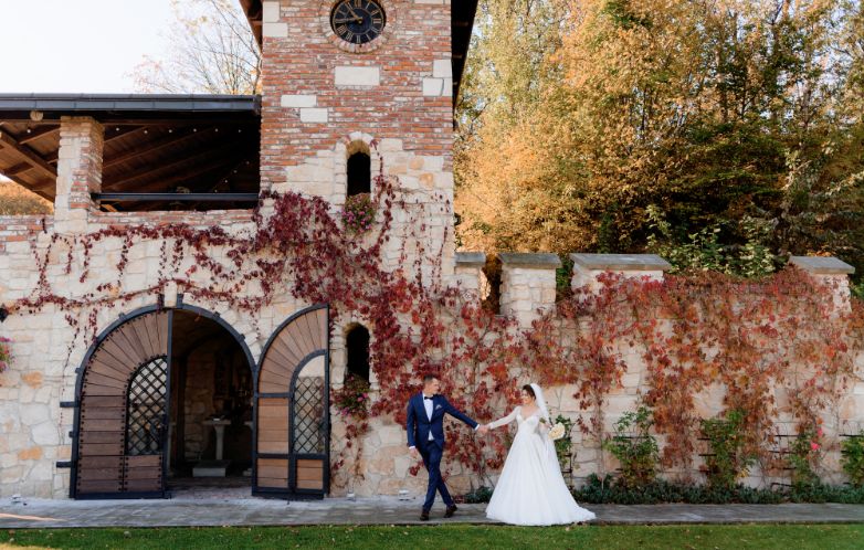 Victorian-wedding-couple-posing-in-front-of-a-wall-full-of-red-flowers